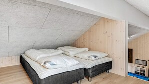 A bedroom with a loft bed, wooden walls, and a sloped ceiling. - 5 Star Holiday Home in Jaegerspris (Jægerspris)