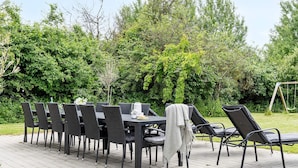 An outdoor dining area with a table and chairs, surrounded by greenery. - 5 Star Holiday Home in Jaegerspris (Jægerspris)