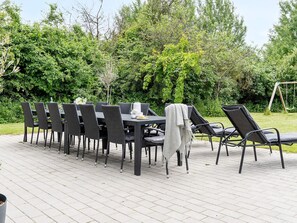 Un área de comedor al aire libre con mesa y sillas, rodeada de follaje.