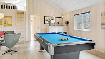 A pool table in a room with wooden walls and a window.