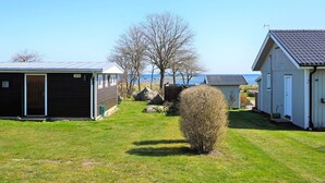 Une rangée de cabanes bordée d’une pelouse, d’un petit arbuste, et offrant une vue dégagée sur l’eau au loin.