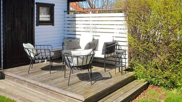 A wooden deck with outdoor seating, a white fence, and a black door.