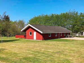 A red single-story building with a sloped roof, a small porch, and a door. - 5 Star Holiday Home in Nordborg (Nordborg)