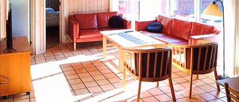 A room with a red sofa, a wooden table, and a television on a wooden cabinet.