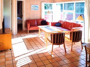 A room with a red sofa, a wooden table, and a television on a wooden cabinet. - 5 Star Holiday Home in Nordborg (Nordborg)