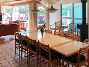 A dining area with a large table, multiple chairs, and a fireplace. - 5 Star Holiday Home in Nordborg (Nordborg)