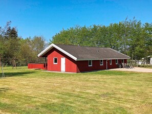 A red single-story building with a sloped roof, a small porch, and a fenced area with outdoor seating.