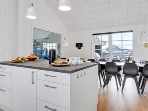 A modern kitchen with a central island, white cabinetry, and a dining area with black chairs. - 5 Star Holiday Home in Sydals (Sydals)