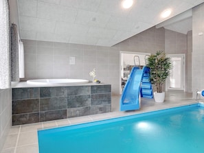 A modern indoor pool area with a blue slide, a hot tub, and a potted plant. - 5 Star Holiday Home in Sydals (Sydals)