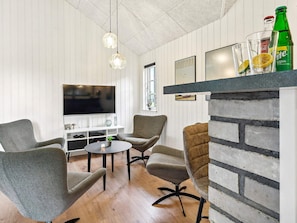 A modern living room with a flat-screen TV, two grey armchairs, a round coffee table, and a brick accent wall. - 5 Star Holiday Home in Sydals (Sydals)