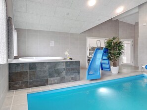 A modern indoor pool area with a blue slide, a hot tub, and a potted plant. - 5 Star Holiday Home in Sydals (Sydals)