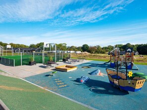A playground with a ship-themed play structure, a basketball court, and picnic tables. - 5 Star Holiday Home in Sydals (Sydals)
