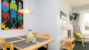 Ett hotellrum med ett matbord, stolar, en lampa, en tv och konstverk på väggen.