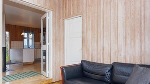 A modern living room with a leather sofa, a wooden coffee table with botanical prints, and a colorful rug. - 4 Person Holiday Home in Ega (Aarhus)