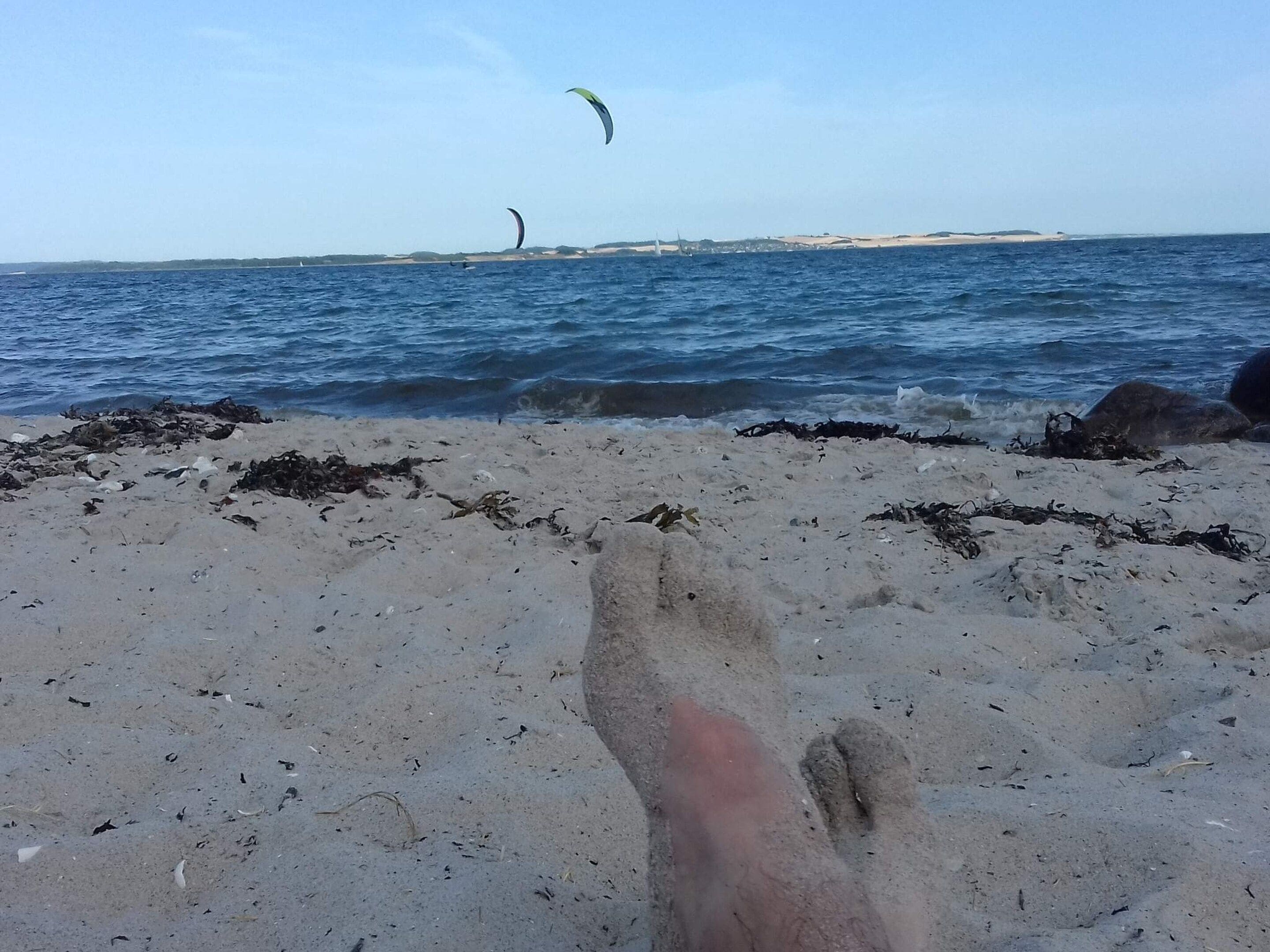 A sandy beach with waves and a distant view of a coastline.