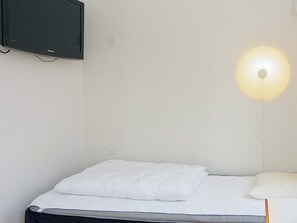 A single bed with white bedding, a wall-mounted television, and a wall-mounted light fixture. - 4 Person Holiday Home in Ega (Aarhus)