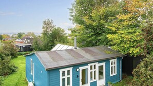 Une petite maison de plain-pied, avec un toit en pente, une porte d’entrée et un petit porche.