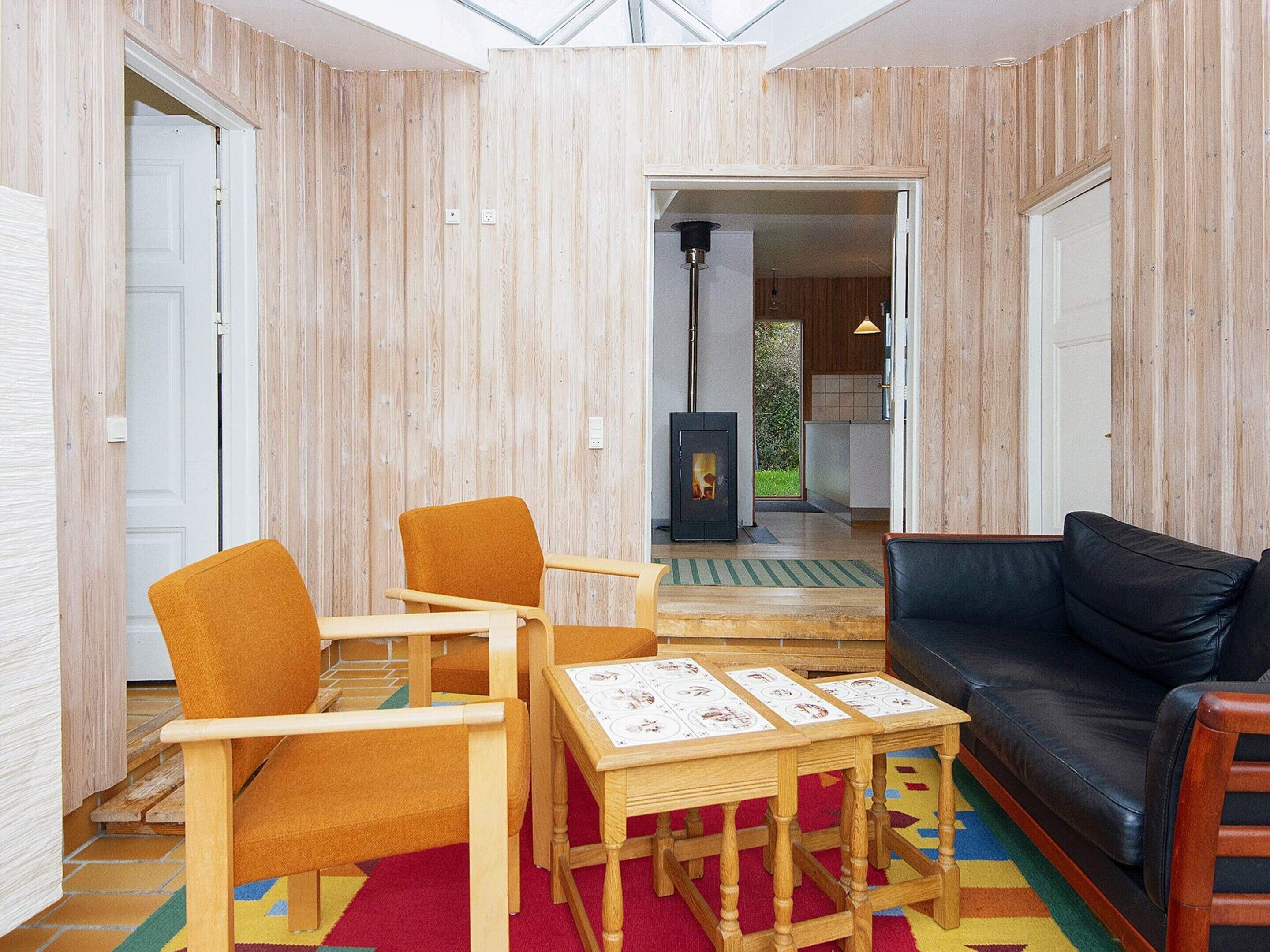 Ein Zimmer mit Kamin, Holzmöbeln und einem schwarzen Ledersofa.