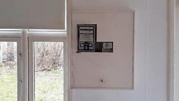 Une porte blanche, ornée d’une petite plaque et dotée d’une fenêtre donnant sur un espace verdoyant.