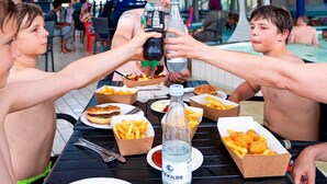 Un groupe de personnes trinquant avec des boissons autour d’une table au bord de la piscine, où sont également disposés des plats et des boissons.