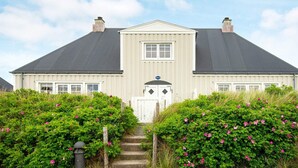 Une maison à deux étages, dotée d’une façade symétrique, d’une entrée centrale avec une porte double et d’un petit porche.