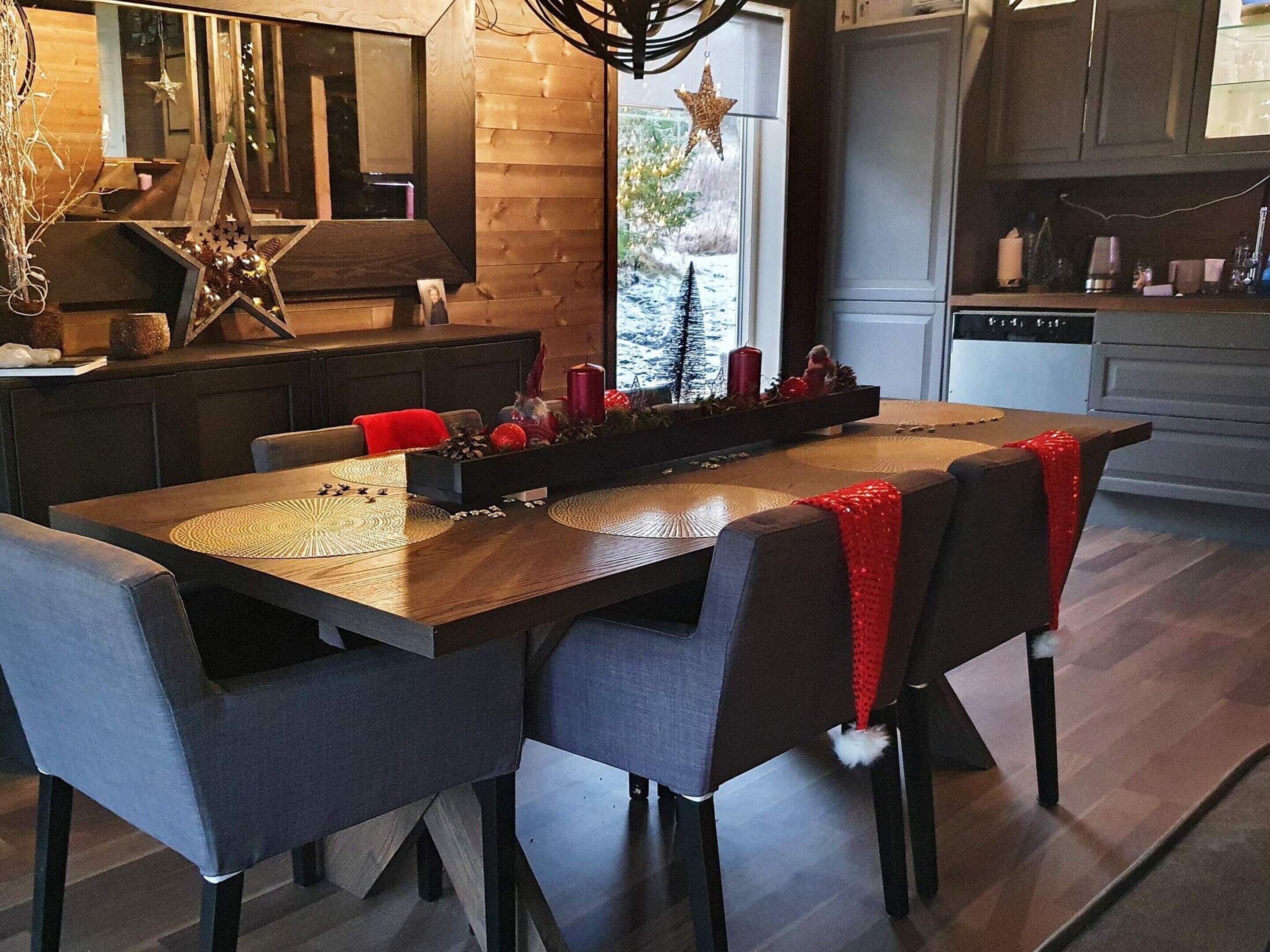 A modern dining area with a wooden table, grey upholstered chairs, and a red decorative element.