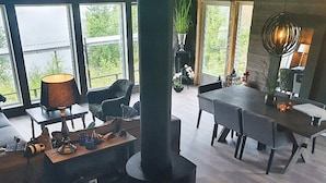 En moderne stue med stort vindue, pejs og spiseområde.