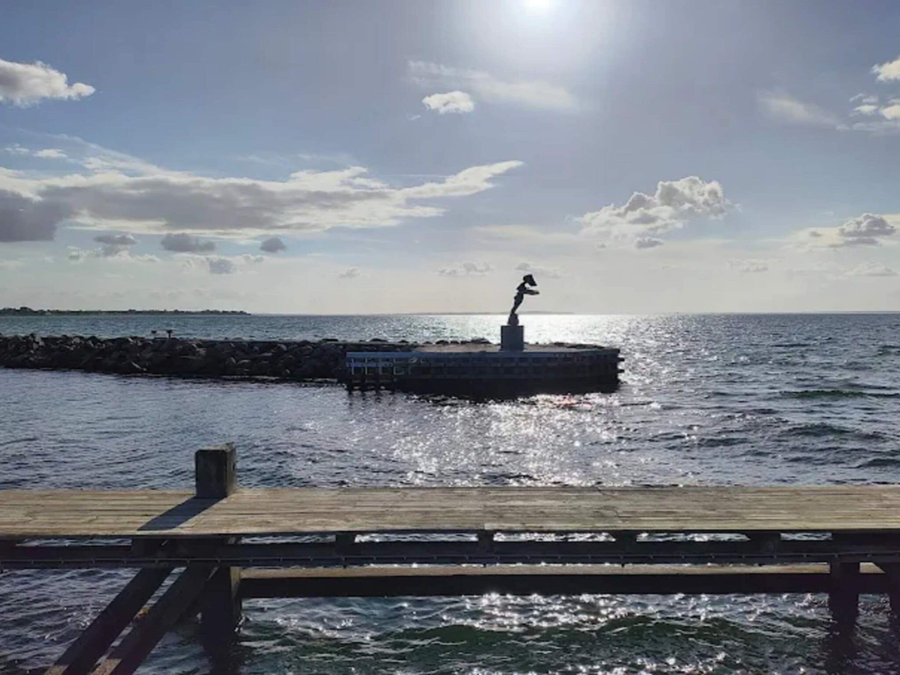 A pier extending into the water with a statue on a platform.