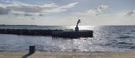 A pier extending into the water with a statue on a platform.