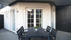 A patio with a table and chairs, a potted plant, and a sliding glass door leading to an interior space. - 5 Person Holiday Home in Bogense (Bogense)