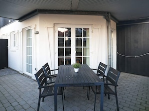 A patio with a table and chairs, a potted plant, and a sliding glass door leading to an interior space. - 5 Person Holiday Home in Bogense (Bogense)