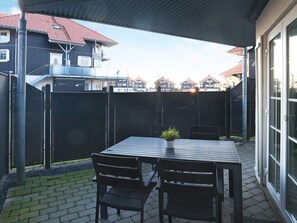 An outdoor patio with a table and chairs, a potted plant, and a view of neighboring houses. - 5 Person Holiday Home in Bogense (Bogense)
