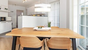 A modern kitchen with white cabinets, a wooden dining table, and two chairs. - 5 Person Holiday Home in Bogense (Bogense)