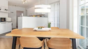 Eine moderne Küche mit weißen Schränken, einem Holztisch und zwei Stühlen.