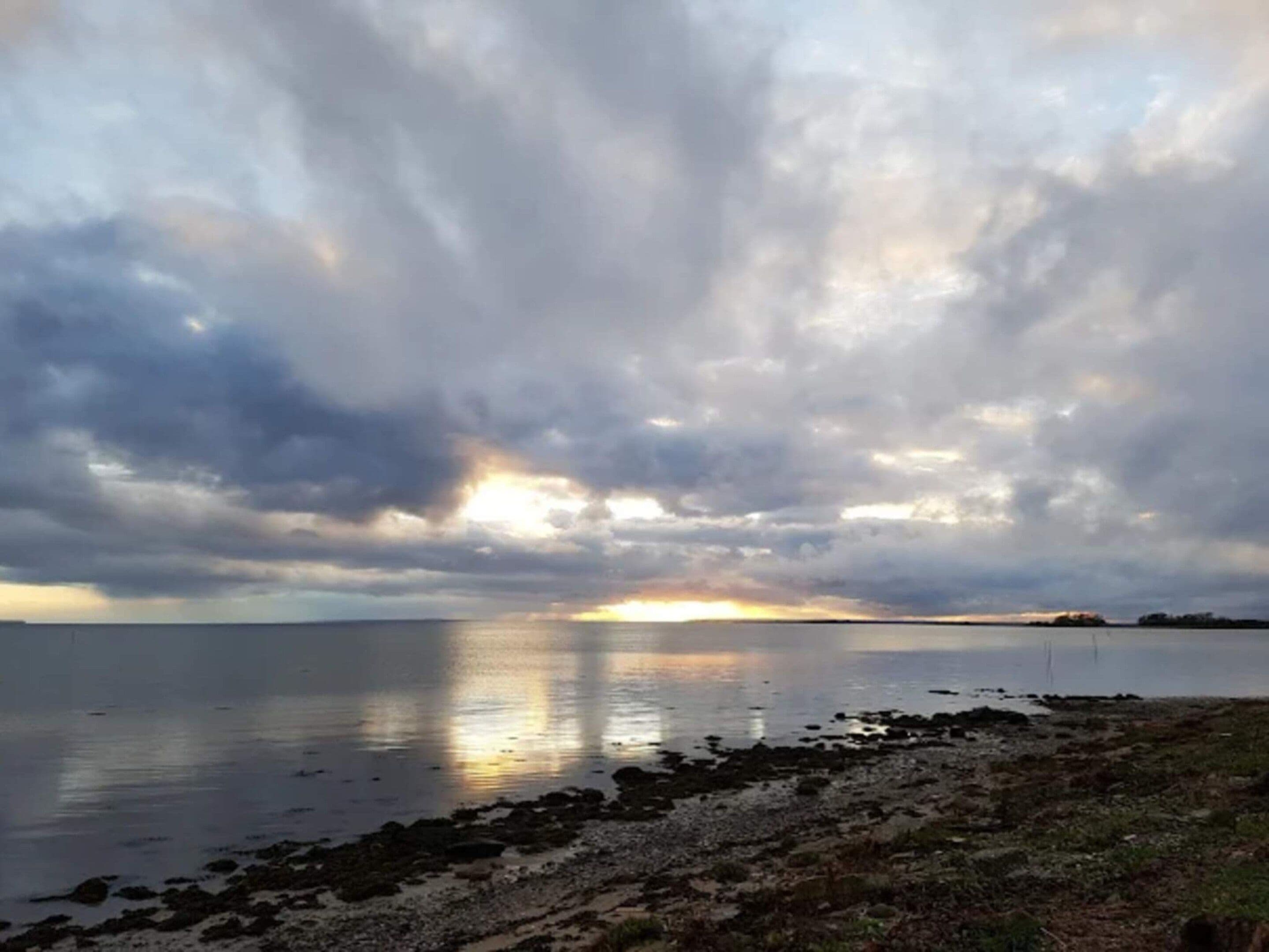 A coastal landscape with a body of water reflecting the sky.
