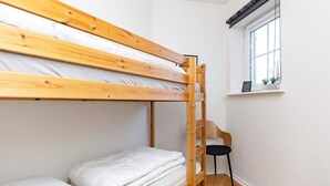 A bunk bed with white bedding, a wooden chair, a small window with a plant, and a tiled floor. - 5 Person Holiday Home in Bogense (Bogense)