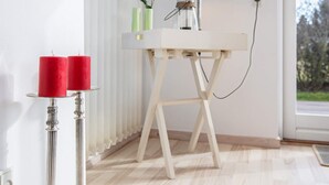 A room with a white table lamp, a white table, and two red candles on a silver candle holder. - 6 Person Holiday Home in Vaeggerlose (Vaeggerlose)