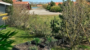 A garden with raised beds, a wooden fence, and a variety of plants. - 6 Person Holiday Home in Vaeggerlose (Vaeggerlose)