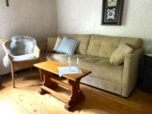 Ein gemütliches Wohnzimmer mit einem Holztisch, einem gepolsterten Sessel und einer Couch.