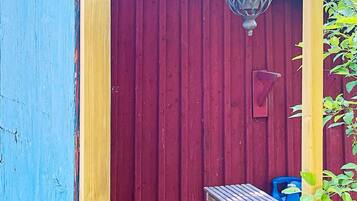 A red wooden door with a small table and a blue container outside.