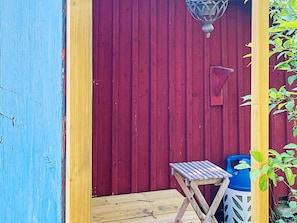 A red wooden door with a small table and a blue container outside.
