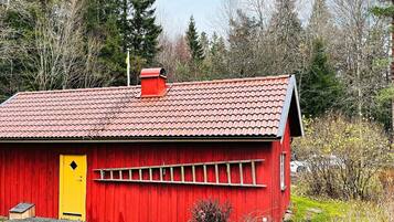 A red wooden building with a yellow door, a red roof, and a small chimney.