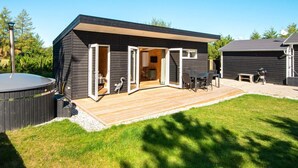 Un espace de vie extérieur moderne comprenant une terrasse, un jacuzzi et un coin barbecue.