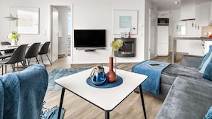 A modern living room with a flat-screen TV, a fireplace, and a dining area with chairs and a table.