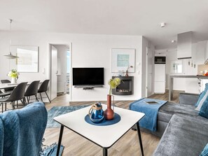 A modern living room with a flat-screen TV, a fireplace, and a dining area with chairs and a table.