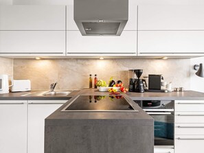Cozinha moderna com ilha central, eletrodomésticos de aço inoxidável e cafeteira.