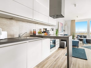 A modern kitchen with a built-in oven, a sink, and a dining area with a view.