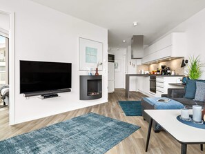 A modern living room with a flat-screen TV, a fireplace, and a dining area with a table and chairs. - 5 Star Holiday Home in Wendtorf (Wendtorf)