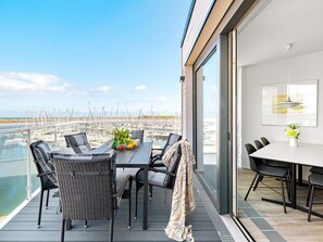 Un balcon avec une table et des chaises, donnant sur une marina où sont amarrés des bateaux.