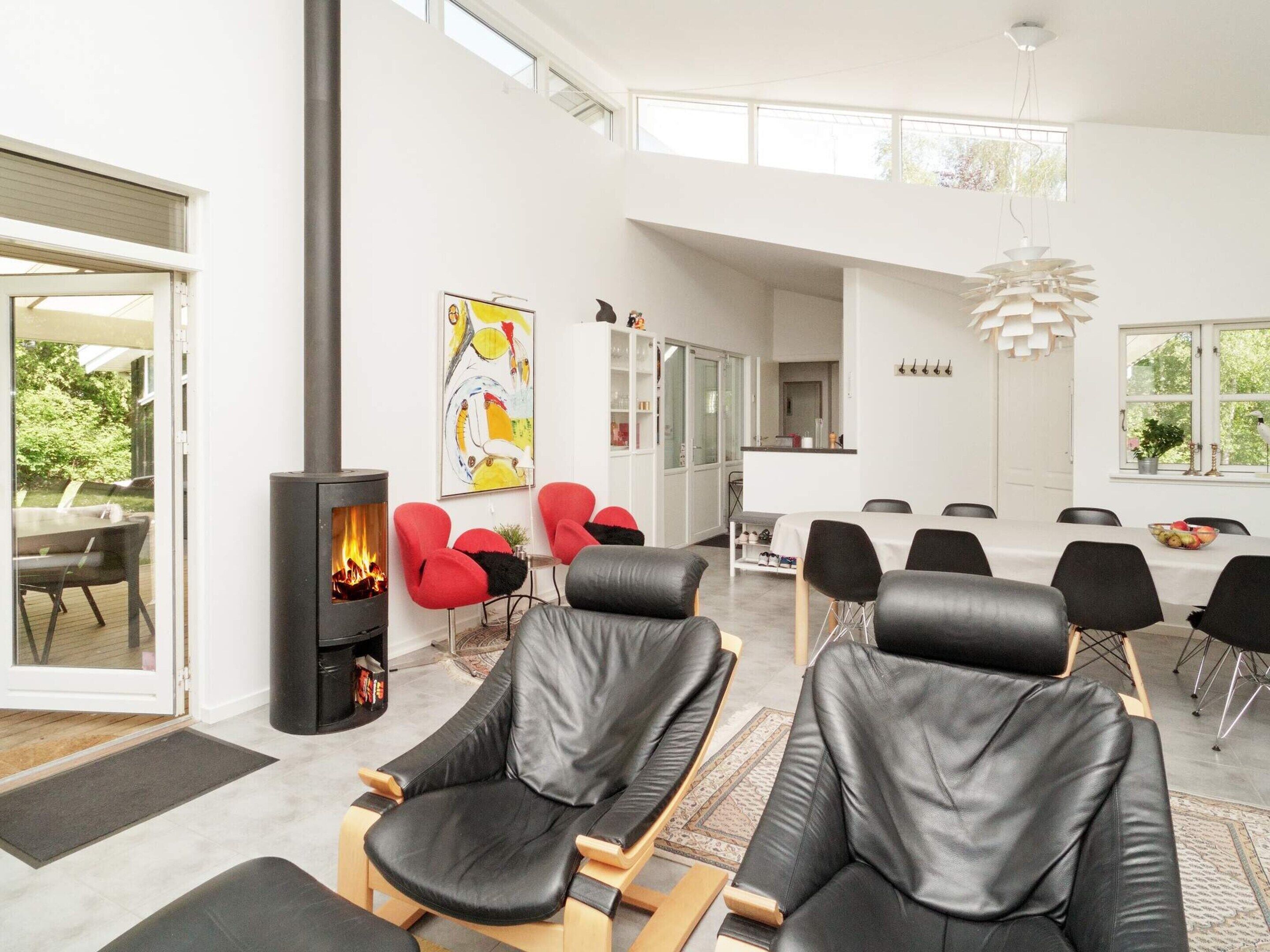 Un interior moderno con chimenea, zona de estar, comedor y vistas al exterior.